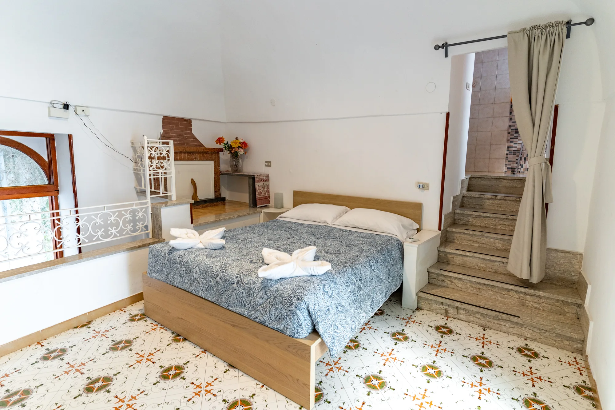 Wide bedroom composition showing bed, stairs and natural window light - interior photography on the Amalfi Coast by Cinereo