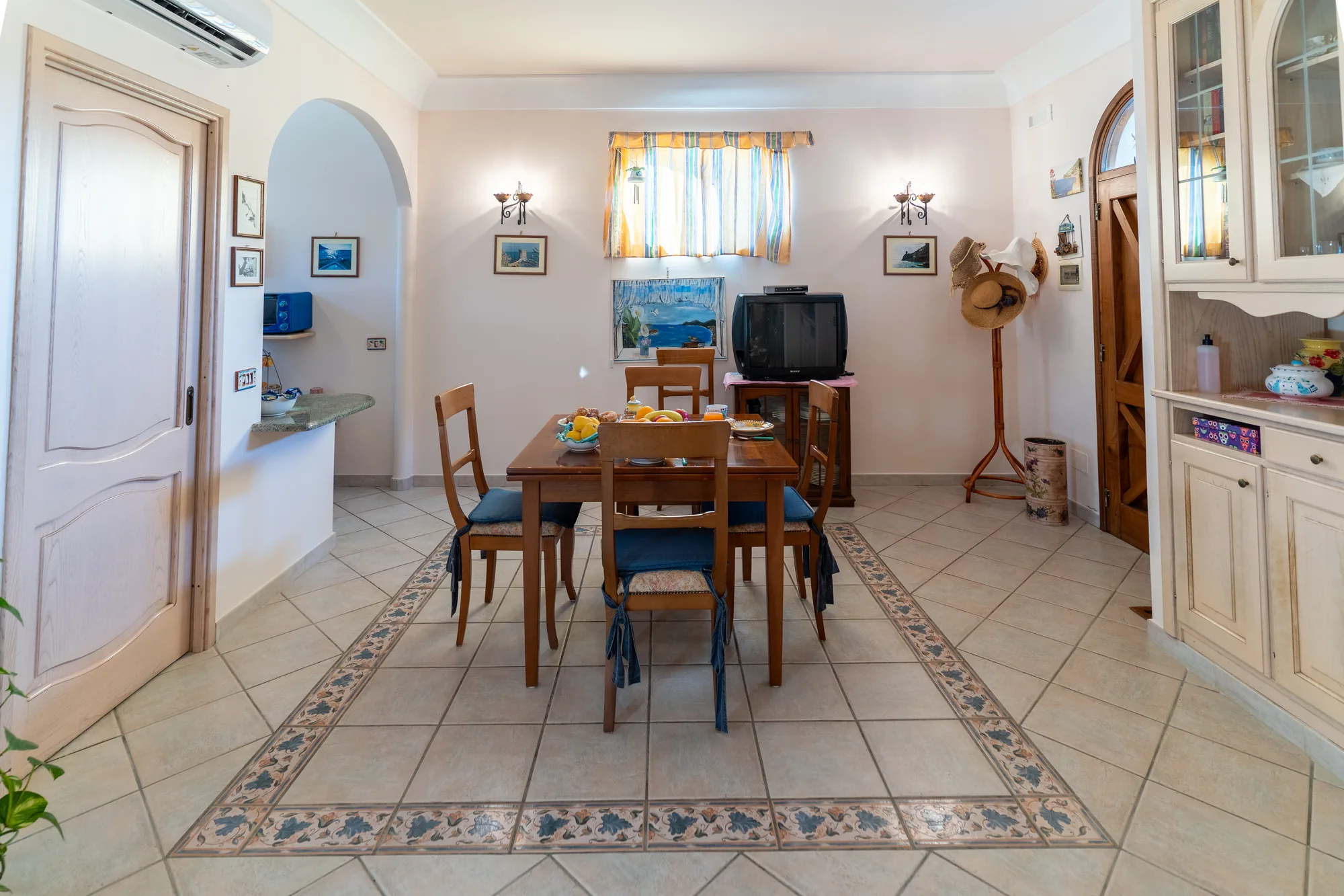 Wide living room angle showing the dining table, entrance and tiled floor - interior photography on the Amalfi Coast by Cinereo