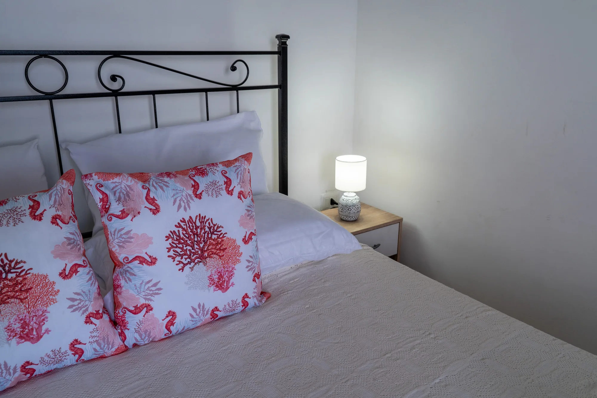 Bed detail with coral pillows and clean morning light - interior photography on the Amalfi Coast by Cinereo