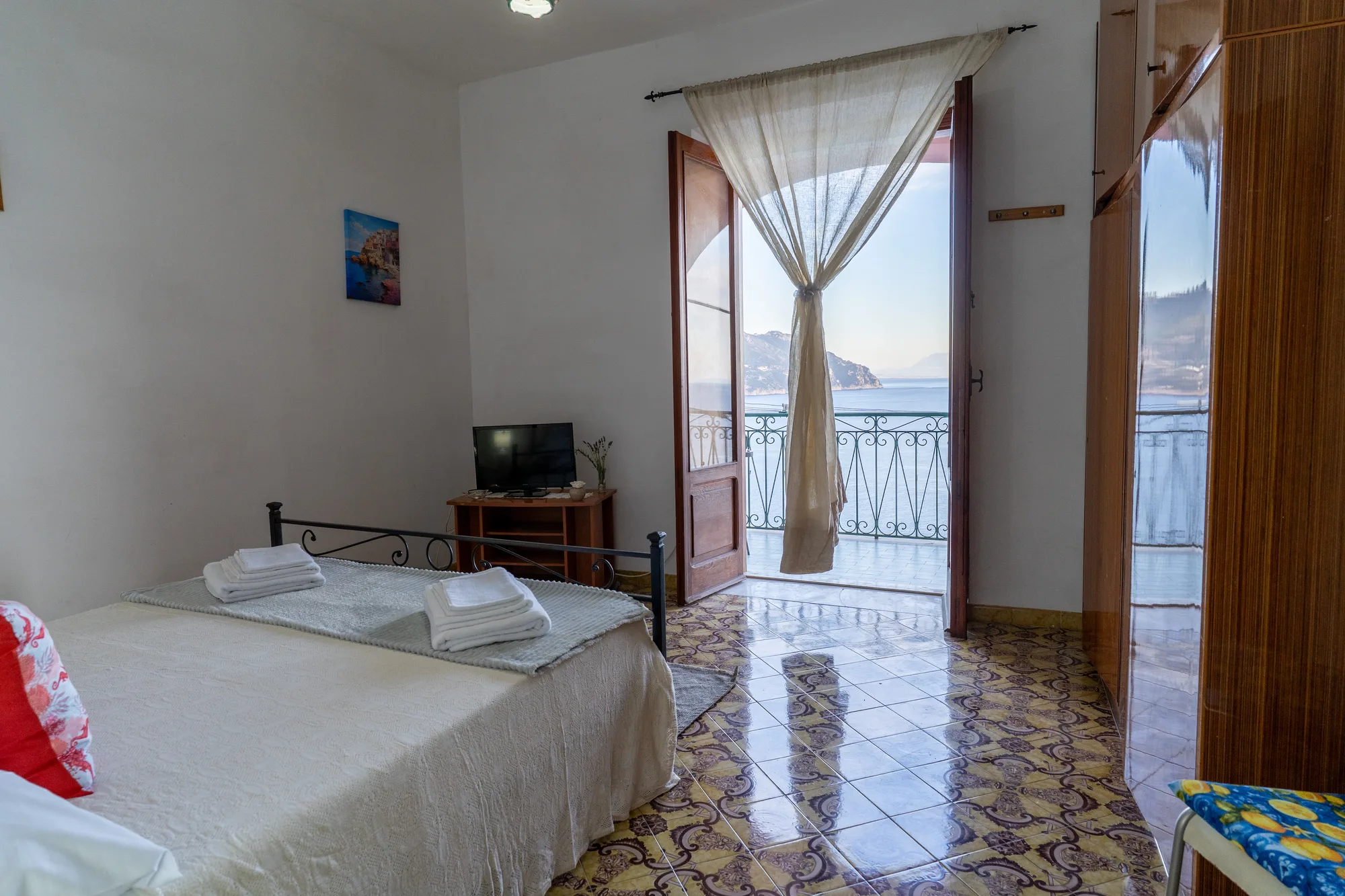Bedroom composition showing bed, television corner and balcony access - interior photography on the Amalfi Coast by Cinereo