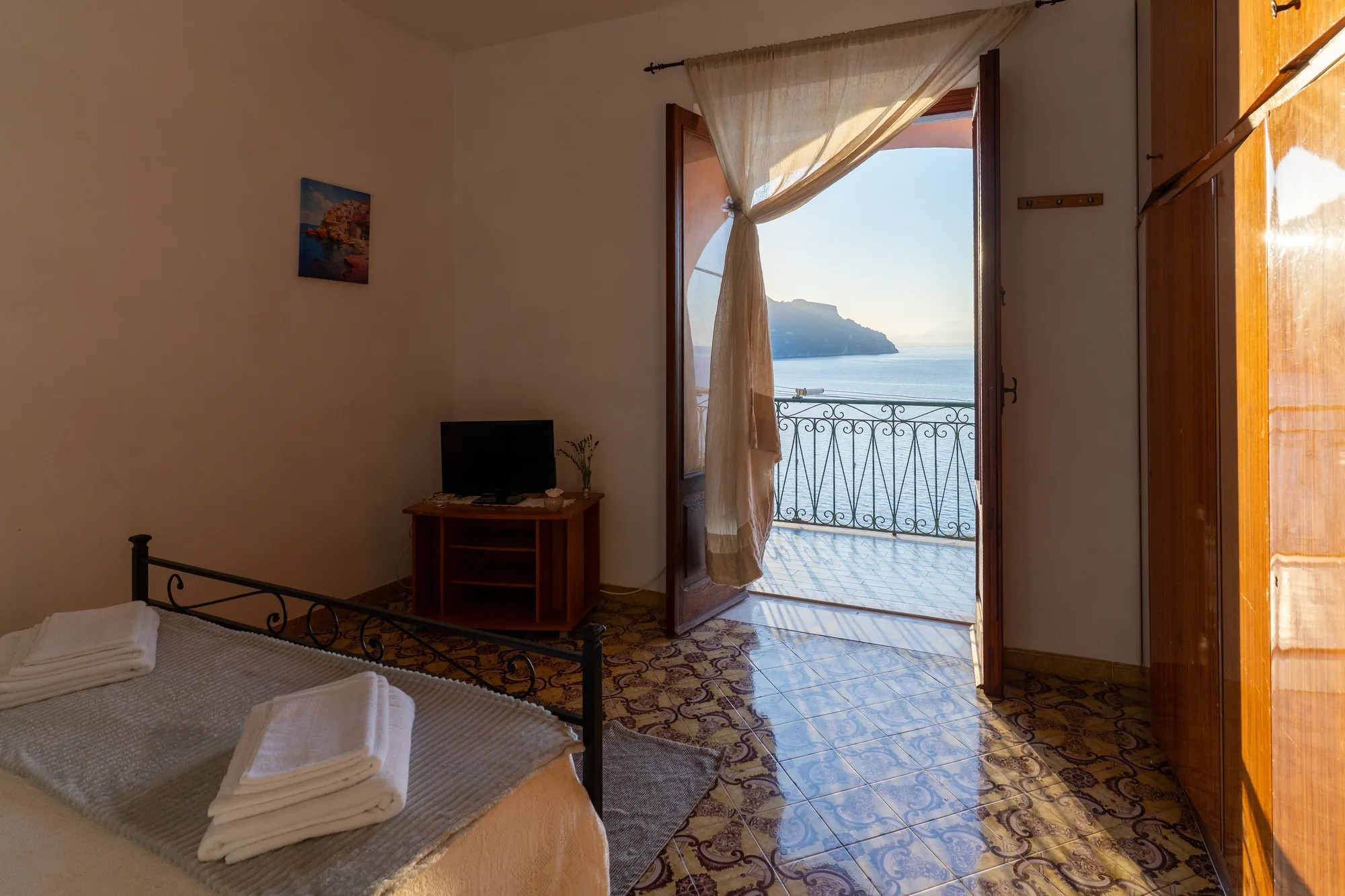 Warm bedroom angle with the Amalfi Coast visible through the door - interior photography on the Amalfi Coast by Cinereo