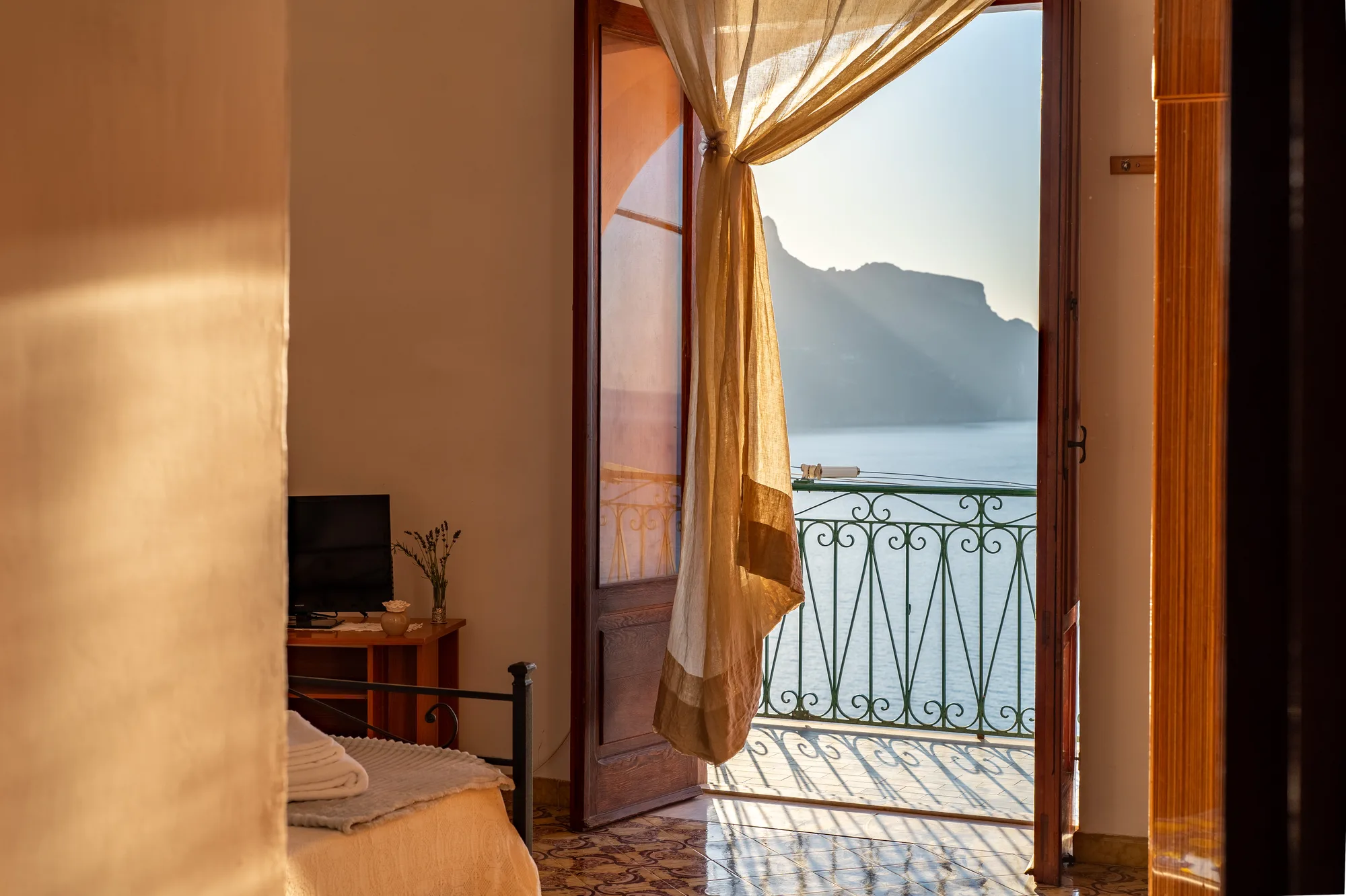 Golden doorway composition with balcony, sea and warm interior wall - interior photography on the Amalfi Coast by Cinereo