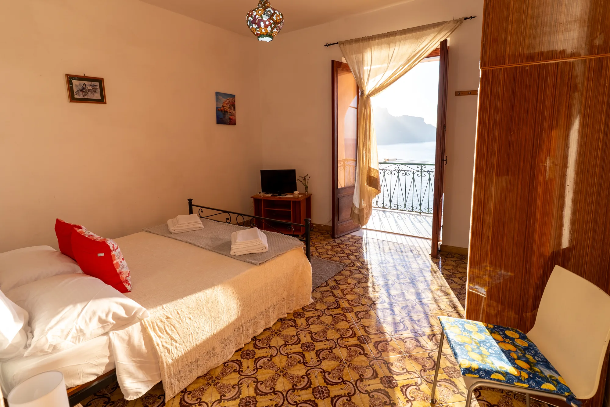 Warm bedroom overview with bed, sofa and open balcony - interior photography on the Amalfi Coast by Cinereo