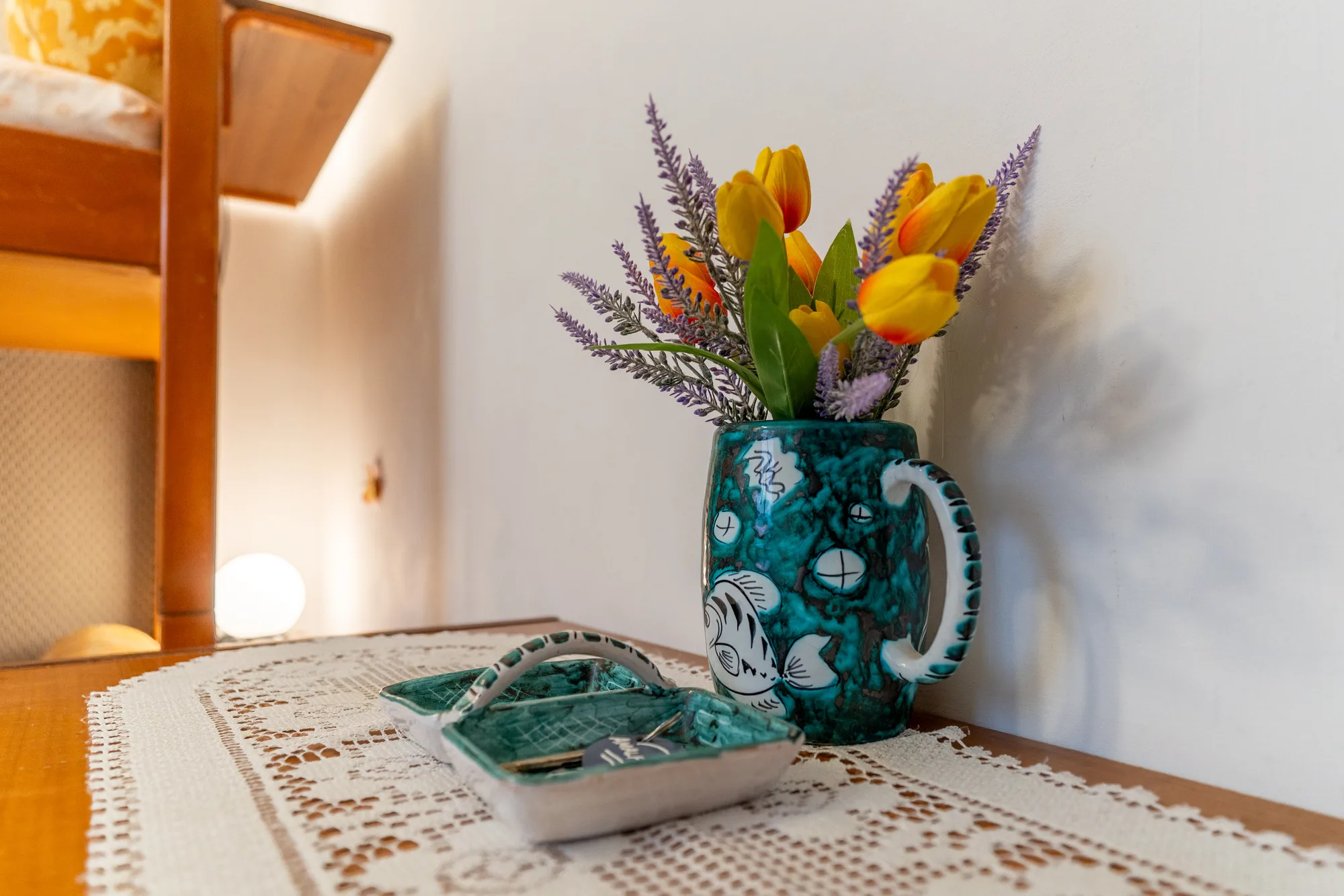 Tabletop flowers and lamp detail adding warmth to a small room - interior photography on the Amalfi Coast by Cinereo