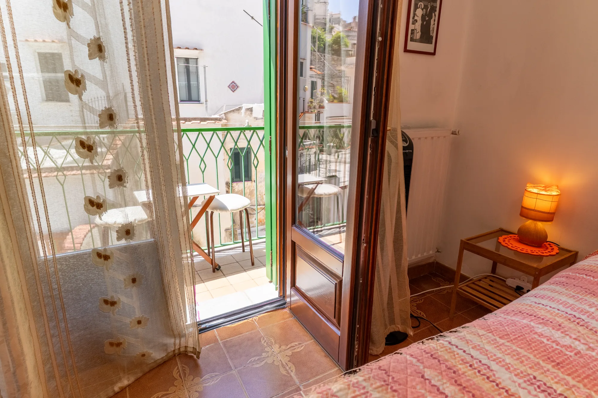 Balcony doorway with warm bedside light and curtain texture - interior photography on the Amalfi Coast by Cinereo