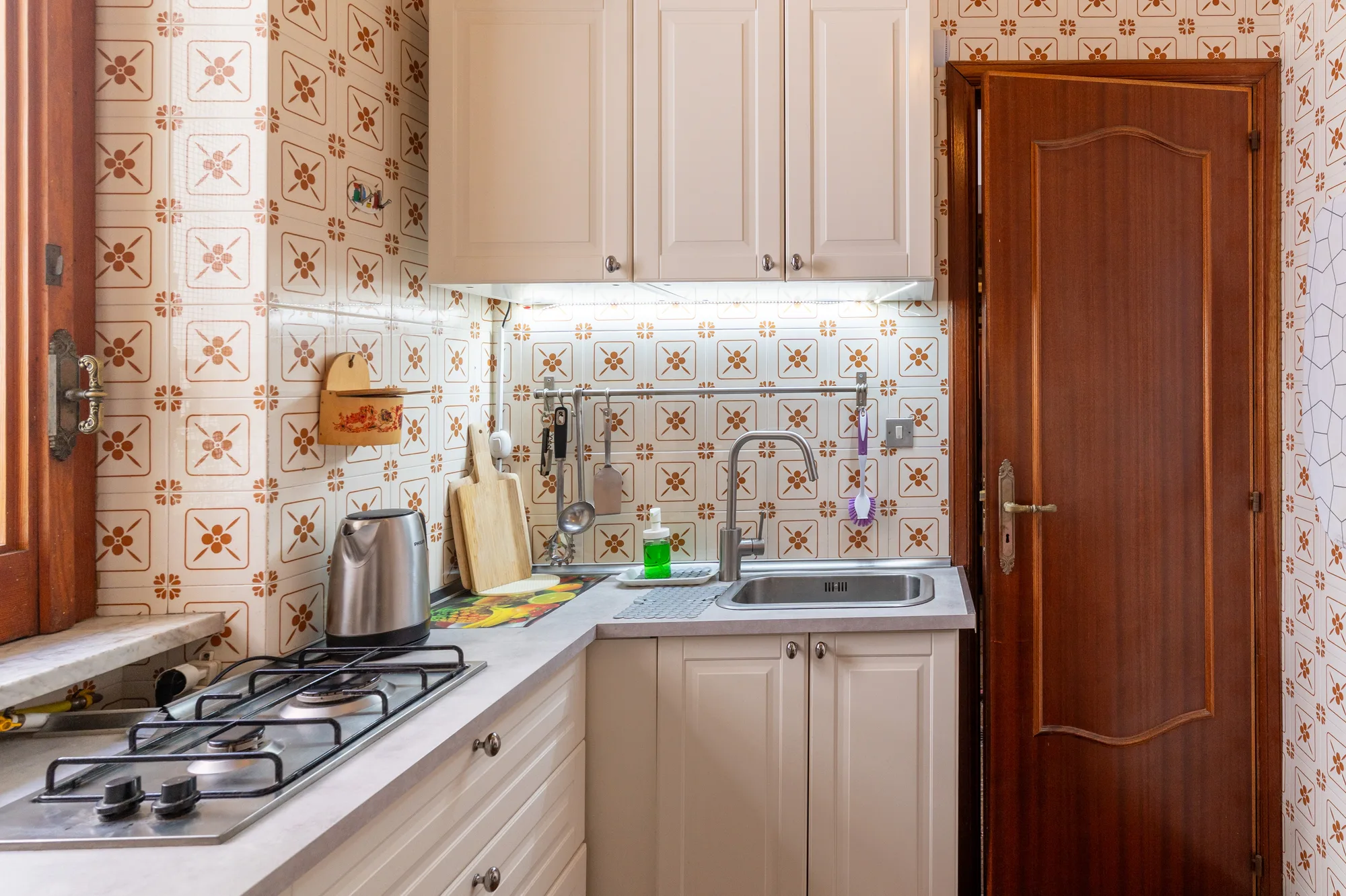 Compact kitchen overview with sink, hob, cabinets and doorway - interior photography on the Amalfi Coast by Cinereo