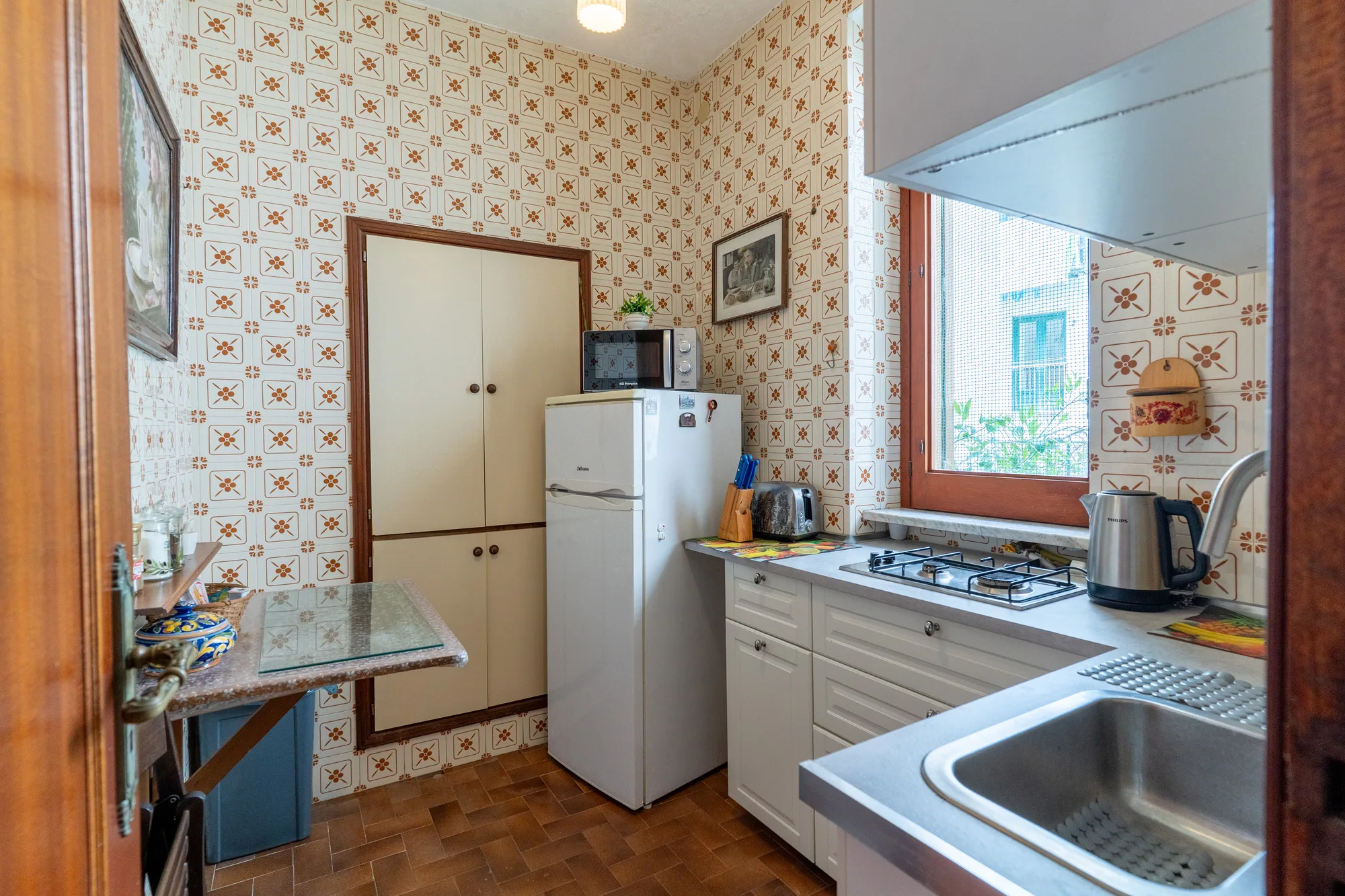Full kitchen view with fridge, sink, counter and natural daylight - interior photography on the Amalfi Coast by Cinereo